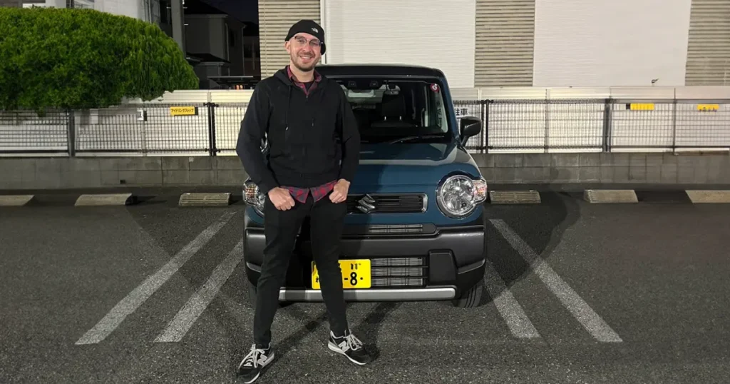 man standing in front of a suzuki hustler